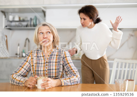 Offended elderly woman listens to complaints from her daughter at home Offended elderly woman listens to complaints from her daughter at home 135929536