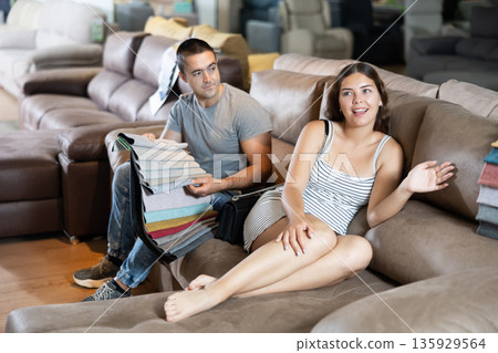 Man with his girlfriend are choosing modern materials for furniture for their home in furniture store Man with his girlfriend are choosing modern materials for furniture for their home in furniture store 135929564