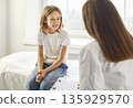 Female doctor talking with a child boy patient during medical examination in clinic. 135929570