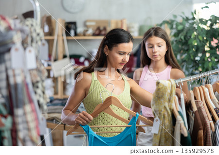 Mother and teenage daughter choosing something for summer in clothing store Mother and teenage daughter choosing something for summer in clothing store 135929578