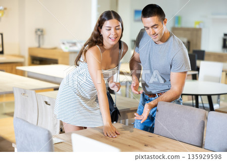 Positive couple choosing dining table in furniture store 135929598