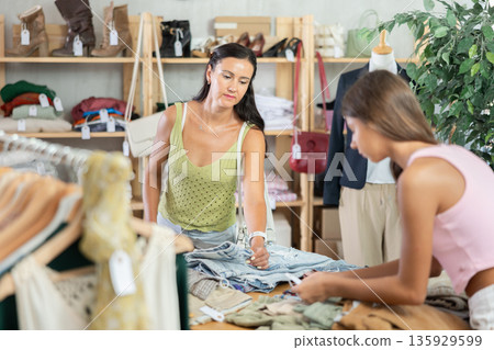Family customer choose denim jeans or shorts in store Family customer choose denim jeans or shorts in store 135929599