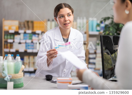 Pharmacist processing order for female customer at pharmacy 135929600