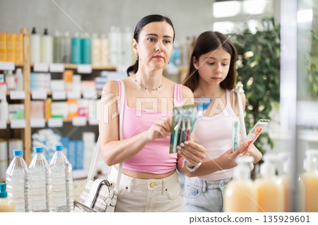 Mother and daughter choose toothbrushes at the pharmacy Mother and daughter choose toothbrushes at the pharmacy 135929601
