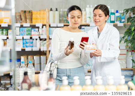 Woman checking composition of medication online at pharmacy 135929615
