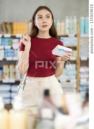 Young woman customer choosing pills in box in drugstore Young woman customer choosing pills in box in drugstore 135929618