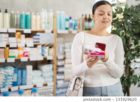 Middle-aged woman customer scanning QR-code on paracetamol box Middle-aged woman customer scanning QR-code on paracetamol box 135929620