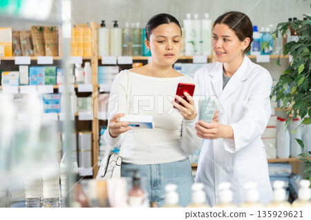 Woman scanning ointment while pharmacist offering friendly support 135929621