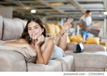 Pretty female is testing new sofa in furniture store Pretty female is testing new sofa in furniture store 135929642