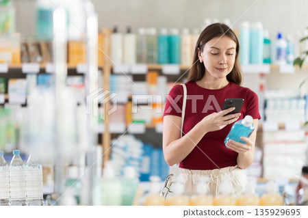 Young woman scanning QR-code on mouthwash liquid in drugstore Young woman scanning QR-code on mouthwash liquid in drugstore 135929695
