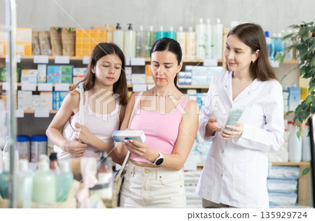 Woman with daughter choosing ointment with pharmacist 135929724