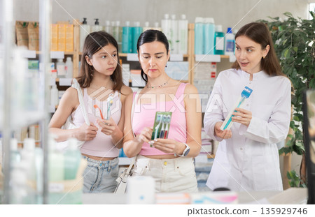 Woman with daughter choosing toothbrush with pharmacist Woman with daughter choosing toothbrush with pharmacist 135929746