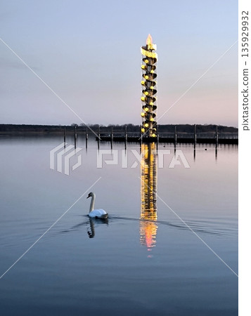 The illuminated Pegelturm spiral tower on Lake Goitzsche at dusk 135929932