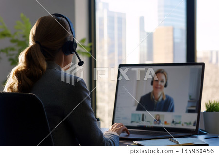 A woman wearing a patterned top is having an over-shoulder view during a virtual meeting. 135930456