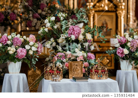 Ornate Church Altar Decorated with Pink and White Flowers, Gold Crowns, and Religious Icons in a Sacred Setting 135931484
