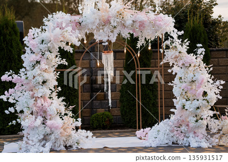 Elegant Wedding Arch?? with White and Pink Flowers and Hanging Beaded Chandelier in Outdoor Garden Setting Elegant Wedding Arch?? with White and Pink Flowers and Hanging Beaded Chandelier in Outdoor Garden Setting 135931517