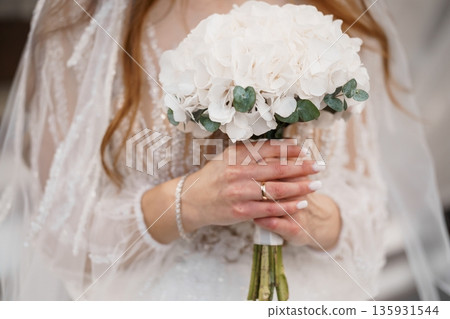 Elegant Bride Holding White Hydrangea Bouquet with Eucalyptus, Soft Lace Dress and Veil in Natural Light Elegant Bride Holding White Hydrangea Bouquet with Eucalyptus, Soft Lace Dress and Veil in Natural Light 135931544