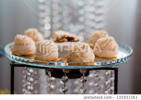 Elegant White Meringue Desserts on Crystal Tray with Sparkling Chandelier Background 135931561