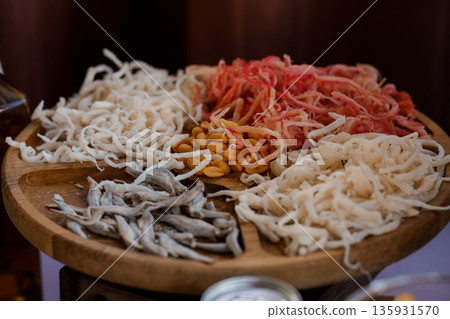 Assorted Dried Seafood Platter Featuring White Fish Strands, Red Shrimp, Peanuts, and Small Silver Fish on Wooden Tray Assorted Dried Seafood Platter Featuring White Fish Strands, Red Shrimp, Peanuts, and Small Silver Fish on Wooden Tray 135931570