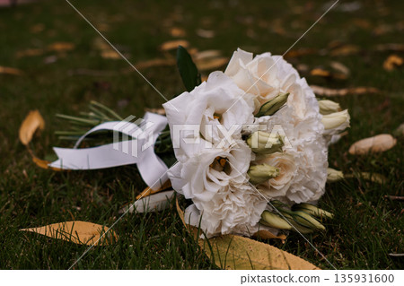 White Eustoma and Rose Bouquet with Ribbon on Grass with Fallen Leaves Autumn Wedding Flowers 135931600