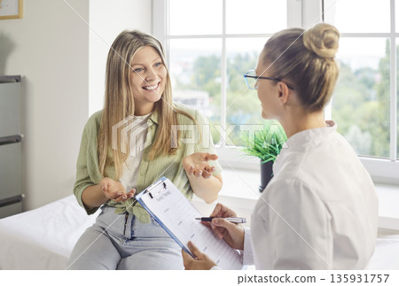 Smiling patient talking with female doctor during healthcare appointment in clinic Smiling patient talking with female doctor during healthcare appointment in clinic 135931757