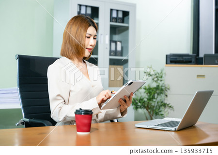Business woman using tablet and laptop for doing math finance on an office desk, tax, report, accounting, statistics, and analytical research concept in office Business woman using tablet and laptop for doing math finance on an office desk, tax, report, accounting, statistics, and analytical research concept in office 135933715