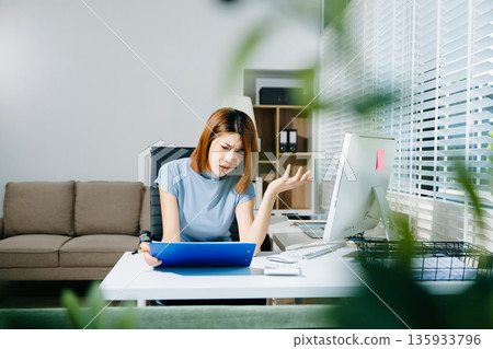 Asian woman feeling migraine head strain.Overworked businesswoman financier while working on laptop and tablet at office. Asian woman feeling migraine head strain.Overworked businesswoman financier while working on laptop and tablet at office. 135933796