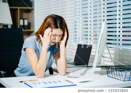 Asian business woman is stressed, bored, and overthinking from working on a tablet at the modern office. Asian business woman is stressed, bored, and overthinking from working on a tablet at the modern office. 135933800