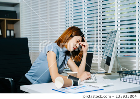Asian business woman is stressed, bored, and overthinking from working on a tablet at the modern office. Asian business woman is stressed, bored, and overthinking from working on a tablet at the modern office. 135933804