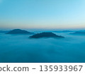Aerial view of flowing fog waves on mountain tropical rainforest,Bird eye view image over the clouds Amazing nature background with clouds and mountain peaks in Thailand 135933967