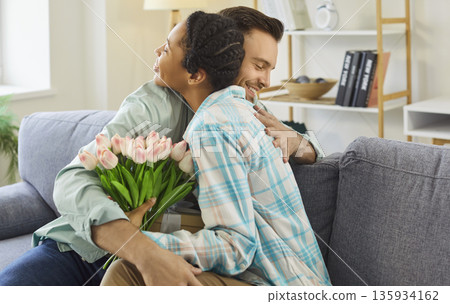 Happy woman hugs her boyfriend thanking him for a gift and flowers 135934162