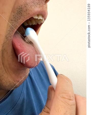 Middle-aged man using a tongue brush Middle-aged man using a tongue brush 135934189