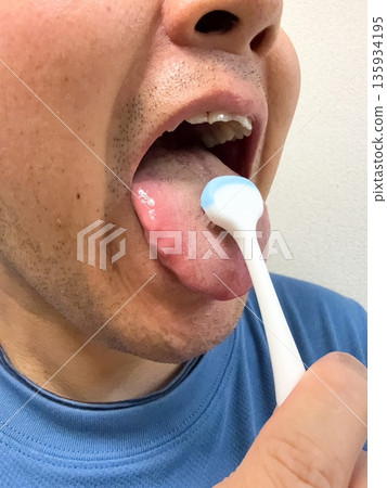 A man taking care of his mouth by brushing his tongue 135934195