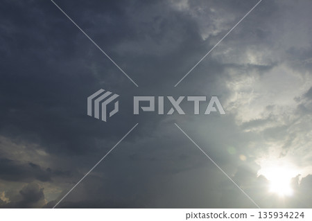 It's a dark cloudy sky with sunlight shining through 135934224