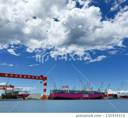 A container ship under construction and a huge crane A container ship under construction and a huge crane 135934318