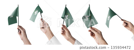 The Macao flag in hand in different angles on a white background 135934472