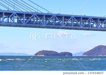 從岩黑島黑濱海灘望去，可以看到一列火車正從瀨戶內大橋（瀨戶內大橋線）下方穿過。 135934607