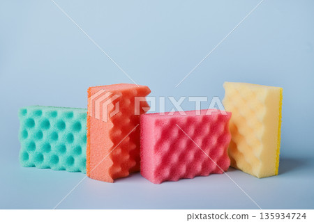 Colorful kitchen sponges with soap gel and bubbles on blue background Colorful kitchen sponges with soap gel and bubbles on blue background 135934724