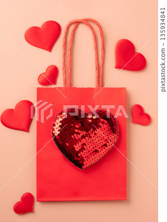 Red gift bag with sequin heart and decorative hearts on pastel background Red gift bag with sequin heart and decorative hearts on pastel background 135934841