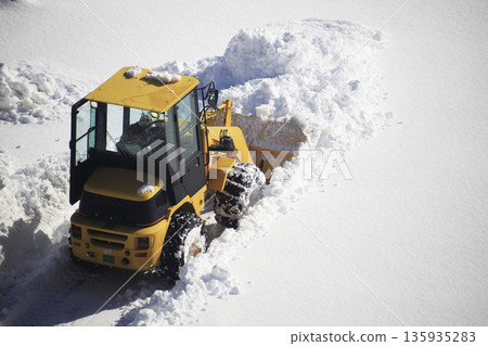 Snow removal vehicle clearing a snow-covered parking lot Snow removal vehicle clearing a snow-covered parking lot 135935283