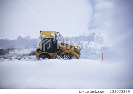 Snow removal vehicle clearing a snow-covered parking lot Snow removal vehicle clearing a snow-covered parking lot 135935289
