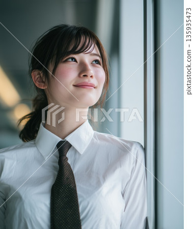 Young Japanese businesswoman looking out the window in an office building 135935473