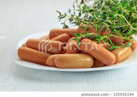 Boiled sausages with thyme on a white wooden table. Boiled sausages with thyme on a white wooden table. 135936194