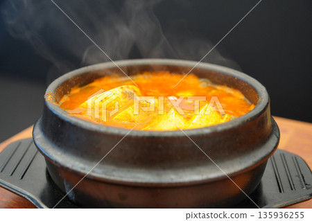 Steaming hot Korean spicy tofu stew (Sundubu-jjigae) served in a traditional earthenware pot (Ttukbaegi) 135936255