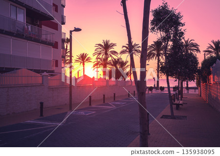 A deserted street leading to the embankment in the early morning during sunrise. Avenida de Benidorm, Sant Joan d'Alacant, Alicante, Spain 135938095