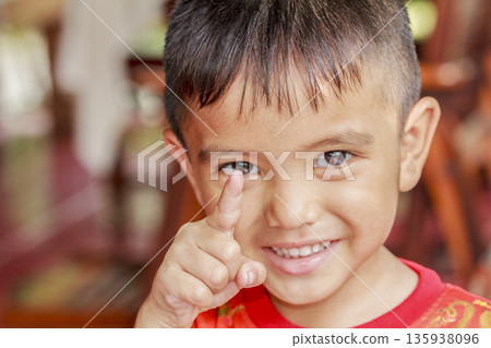 Portrait of a cute Asian little boy show one finger to camera with a blurry face 135938096