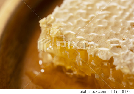 一張特寫微距照片,展示了蜂巢蜜溢出的金色蜂蜜。 一張特寫微距照片,展示了蜂巢蜜溢出的金色蜂蜜。 135938174