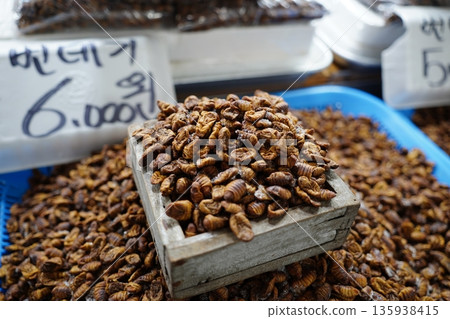 Close-up of Korean traditional market delicacy boiled silkworm pupae (Beondegi) displayed on trays, a popular high-protein snack Close-up of Korean traditional market delicacy boiled silkworm pupae (Beondegi) displayed on trays, a popular high-protein snack 135938415