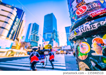Tokyo cityscape in Japan on New Year's Day. The sticker on this pillar is still there. Shibuya in the morning, with inbound tourists continuing to come. Most of them are foreign tourists. Tokyo cityscape in Japan on New Year's Day. The sticker on this pillar is still there. Shibuya in the morning, with inbound tourists continuing to come. Most of them are foreign tourists. 135940510