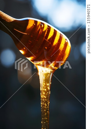 金色的蜂蜜從木湯匙上滴落。 135940571